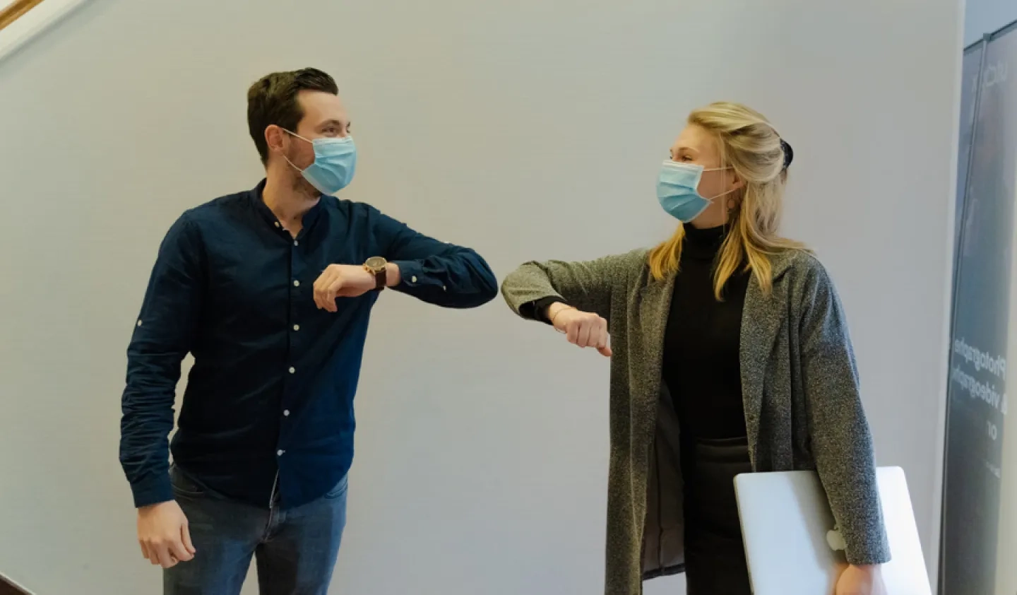 Two masked colleagues bumping elbows