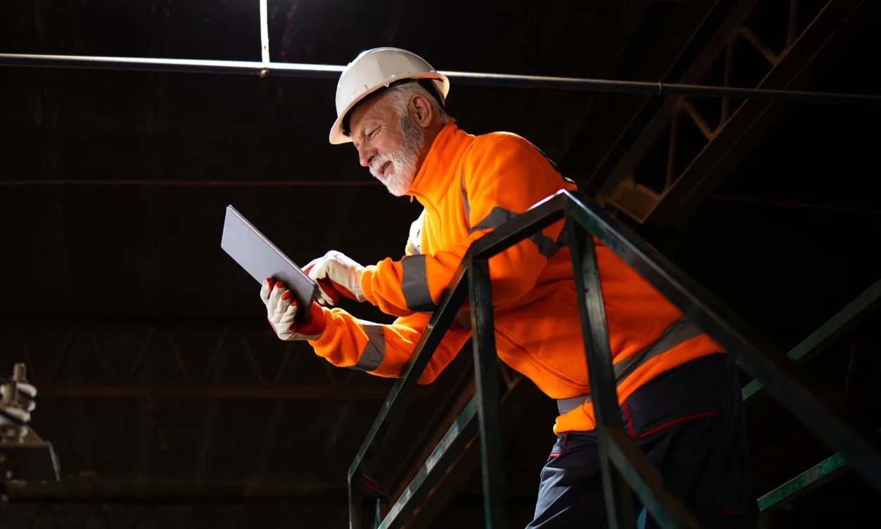 A safety supervisor checking a tablet on a plant floor walkway